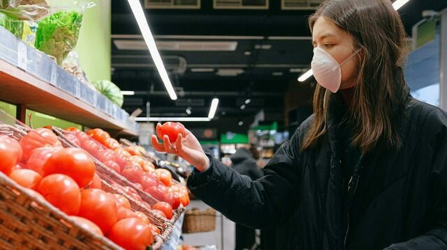Junge Frau mit Mund-Nasen-Schutz beim Einkaufen