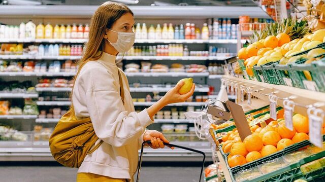Junge Frau mit Mundschutz beim Lebensmitteleinkauf