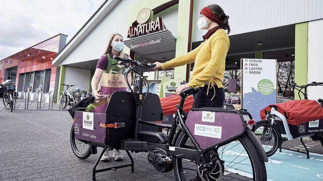 Zwei Frauen mit Lastenrad vor Alnatura Super Natur Markt