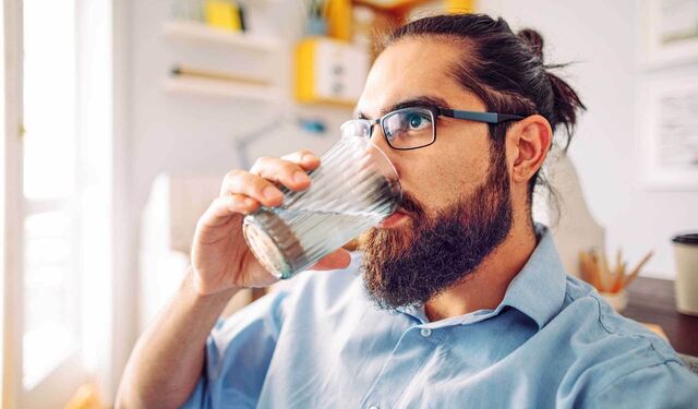 Ein Mann trinkt Wasser aus einem Glas.