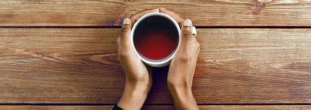 Hände umgreifen eine Tasse mit Tee