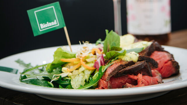 Salat und Rindfleisch auf einem Teller mit Bioland-Fähnchen