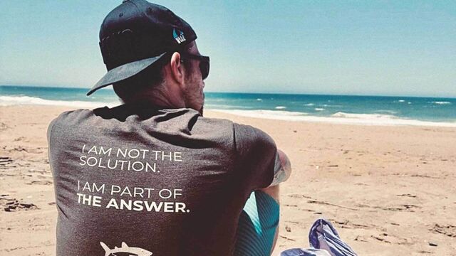 Ozeankind-Mitgründer Michael Schmidt sitzen, von hinten, am Strand