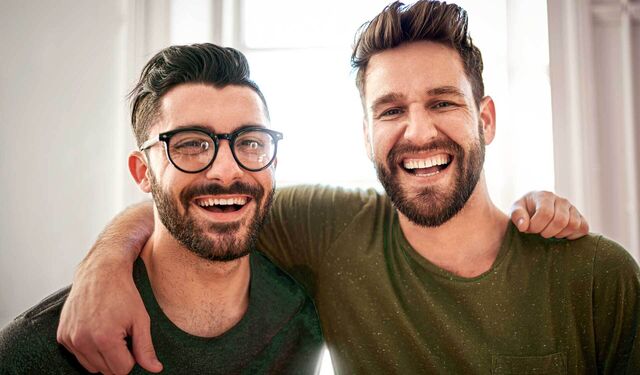 Zwei Männer mit Bärten sehen lächelnd in die Kamera
