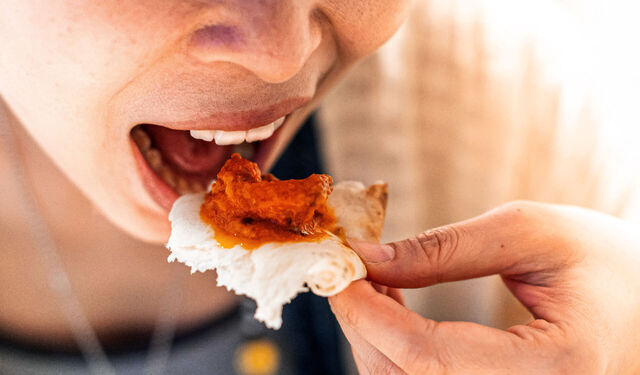 Eine Person steckt sich ein Stück Naan Brot mit Curry in den Mund